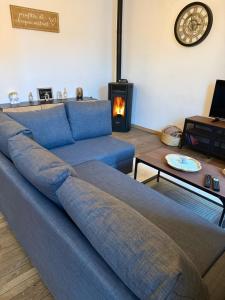 a blue couch in a living room with a fireplace at Charmant logement au cœur de la nature ardennaise in Habay-la-Neuve