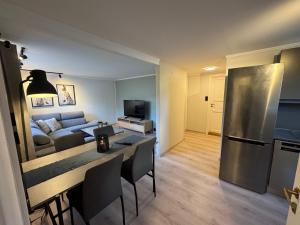 a kitchen and living room with a table and a refrigerator at Cozy and centrally located apartment in Tromsø
