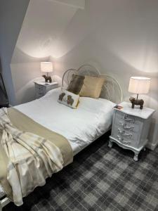 a bedroom with a bed and two night stands with lamps at Glenburn Cottage in Kirkmichael