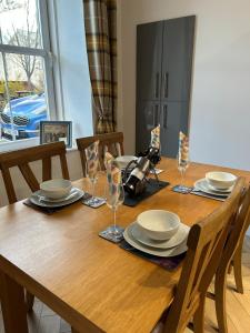 a wooden table with plates and glasses on it at Glenburn Cottage in Kirkmichael