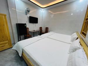 a bedroom with a white bed and a flat screen tv at Nhà Nghỉ Hoàng Yến in Cái Răng