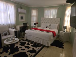 a bedroom with a bed and a chair and a couch at Apelles Palace Guest House - Staycation of choice - Home away from yours in Tlokweng