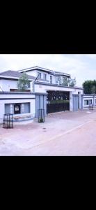 a large white building with a courtyard in front of it at Apelles Palace Guest House - Staycation of choice - Home away from yours in Tlokweng