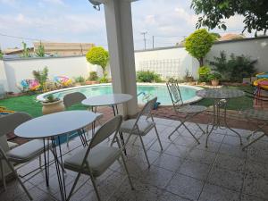 a patio with tables and chairs next to a swimming pool at Apelles Palace Guest House - Staycation of choice - Home away from yours in Tlokweng +4 photos