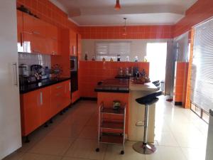 a kitchen with orange cabinets and a black counter at Apelles Palace Guest House - Staycation of choice - Home away from yours in Tlokweng