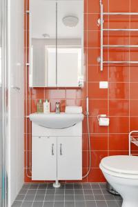 a bathroom with a white sink and orange tiles at Aurora Atelier in Rovaniemi +20 photos