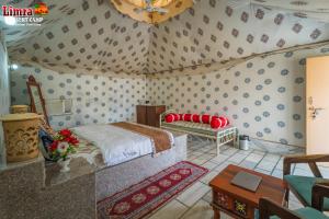 Desert Marvadi Resort في Sām: غرفة نوم بها سرير وأريكة في الغرفة