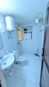 a bathroom with a toilet and a sink and a fan at Meera 1 bhk Palace Omaxe in Vrindāvan +8 photos