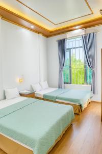 two beds in a room with a window at Tiến Dũng Motel Thanh Hoá in Thanh Hóa