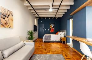 un salon avec un lit et des murs bleus dans l'établissement Copan Castelli Studios SP, à São Paulo