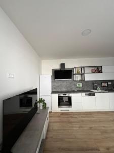 a kitchen with white cabinets and a wooden floor at Central and Spacious Apartment with All Amenities in Nitra