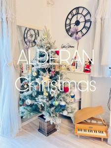 een kerstboom in een woonkamer met een klok bij Orbit ALDERAN-Home Stay in Matsuda