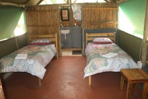a room with two beds and a table in it at Amangwane Tented Camp in Enkovukeni +16 photos