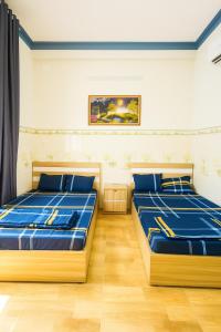 two beds in a room with blue sheets at Hoàng Gia 2 Motel Long An in Ðức Hòa
