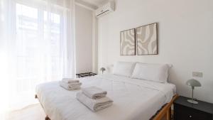 biała sypialnia z dużym łóżkiem i ręcznikami na nim w obiekcie Italianway - Negroli 11 w Mediolanie