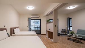 a hotel room with two beds and a desk at Water Woods Inn in Kaohsiung