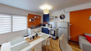 a kitchen with orange walls and a table with chairs at T2 Cozy & Elegant, 5 min walk to Nausicaá in Boulogne-sur-Mer