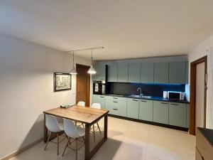 a kitchen with a wooden table and white chairs at Pragma Apartments - Appartamento Dellantonio in Predazzo