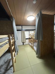 a room with two bunk beds and a window at ゲストハウスはれのち in Furunoushigawa