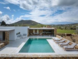 a swimming pool with lounge chairs and a house at Villa Raphael - Luxury and Serenity in Paros in Naousa