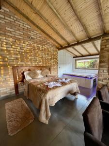 Quiosque Família Chalé Garça في جوانوبوليس: غرفة نوم بسرير كبير في جدار من الطوب