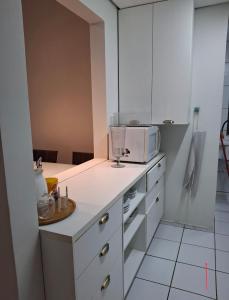 a kitchen with white cabinets and a microwave at Apartamento térreo com 2 quartos e jardim in Teresina +6 photos