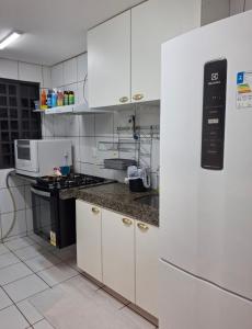 een keuken met witte kasten en een aanrechtblad bij Apartamento térreo com 2 quartos e jardim in Teresina