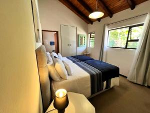 een slaapkamer met een bed met kussens en een raam bij SeaSalt Rest in Plettenbergbaai