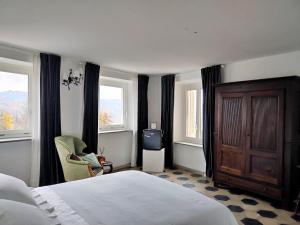 a bedroom with a bed and a chair and windows at Casa Salvàn in Rodello