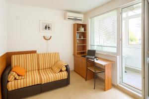 a living room with a chair and a desk with a laptop at Family 2BDR Apartment in the City Center in Sveti Vlas