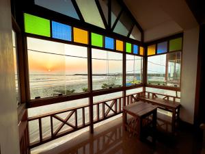 a room with a window with a bench and a view of the beach at SeaCret by Dormer Stay in Kozhikode +11 photos