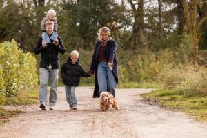 a group of people walking a dog on a dirt road at Hofparken Wiltershaar in Winterswijk