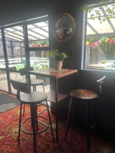 a table and two stools in a room with a window at Nourish Reefton & Wilsons Hotel in Reefton