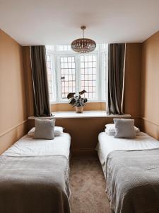 two beds in a room with a window at The Red Lion Inn in Rothwell