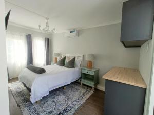 a white bedroom with a bed and a window at Bij De Graaff in Graaff-Reinet