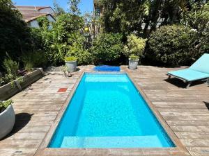 a small swimming pool in a backyard with a chair and a chaise lounge at SeaSalt Escape in Plettenberg Bay