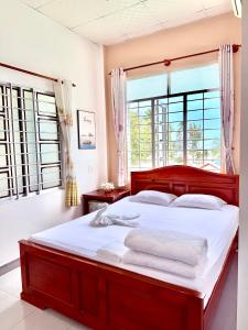 a bedroom with a large bed with white sheets at Quoc Dinh Guest House in Mui Ne