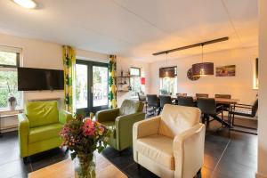 a living room with chairs and a dining room at Zandduin Villa met Sauna | 10 personen in Hooghalen