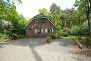a brick house with a driveway in front of it at Zandduin Villa met Sauna | 10 personen in Hooghalen