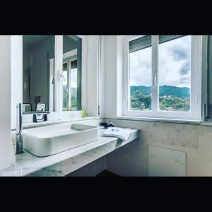 ein weißes Badezimmer mit einem Waschbecken und zwei Fenstern in der Unterkunft Municipio 25 in Corigliano Calabro