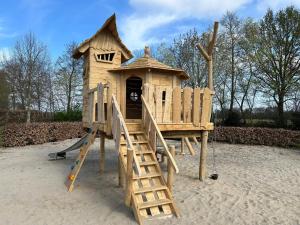 a wooden playground with a slide and a play house at Camping Emmen in Schoonebeek