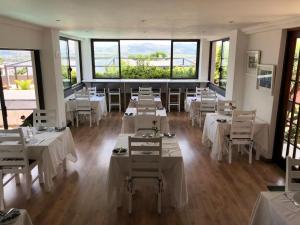 een restaurant met witte tafels, stoelen en ramen bij Bush Baby View Lodge in Hartbeespoort