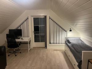 a bedroom with a bed and a desk and a computer at Lofoten - Spacious Room in Vestvågøya