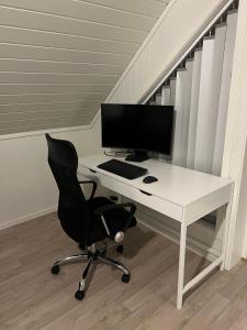 a desk with a computer monitor and a chair at Lofoten - Spacious Room in Vestvågøya