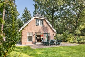 a brick house with tables and chairs in a yard at Stuifzand Bungalow | 8 personen in Hooghalen