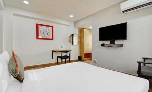 een slaapkamer met een groot wit bed en een flatscreen-tv bij Townhouse Madhyamgram Chowmatha Bus Terminal Kolkata Formerly Star Guest House in Dohāri