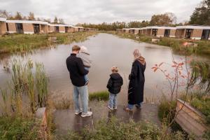a family standing next to a body of water at Hofparken Wiltershaar in Winterswijk