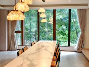a dining room with a large table and chairs and windows at Villa Yin Niseko in Kutchan