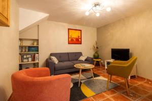 ein Wohnzimmer mit Sofa, Sesseln und Fernseher in der Unterkunft La Maisonnette Etape de Saint-Côme d'Olt in Saint-Côme-dʼOlt