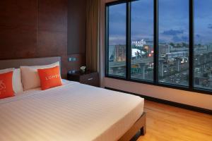 a bedroom with a large bed and a large window at Lumen Bangkok Srinakarin in Bangkok